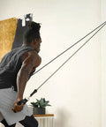 Top Tier Space Saving Home Gym Resistance Band System With Gliding Wall Track Three Foot Aluminum Mount And Five Bands Plus Handles to Kill Your Workout Grind Daily, showing a user exercising with resistance bands.
