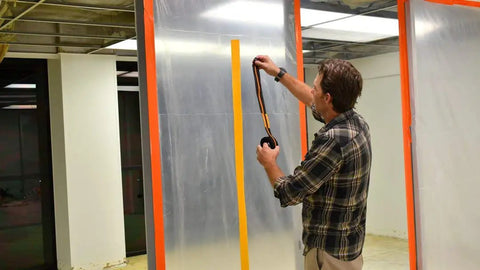 Man applying Mounting Strip Refills 12 Pack For Reusable Dust Barrier Zippers And Magnetic Entry Strips on clear dust barrier.