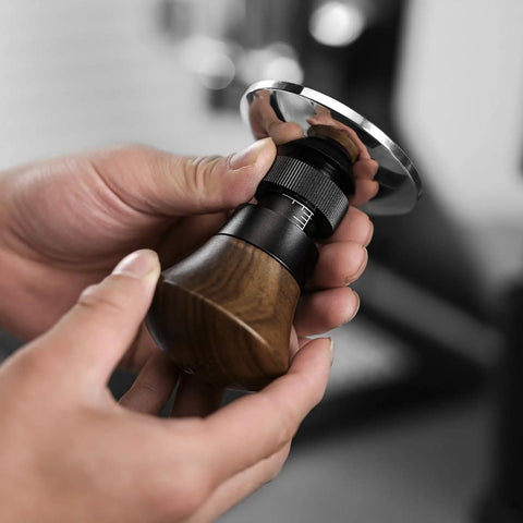 Person holding a 58.35mm Espresso Tamper With Spring Loaded Return And Adjustable Depth Pro Grade Stainless Steel Ripple Base