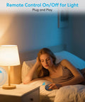 Woman using Wireless Garbage Disposal Switch Kit With Remote Control in bedroom, controlling bedside lamp remotely.