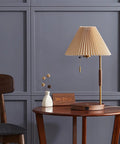 USB Wireless Charging Desk Lamp With Wood And Gold Finish on a wooden table, gray panel wall backdrop