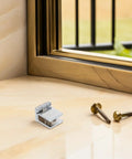 Rock Solid No Drill Glass Door Pivot Hinges That Work Great For Cabinets And Shower Enclosures Built With Strong Zinc Alloy shown with screws on a ledge
