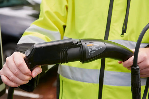 Slick Heavy Duty Type One Electric Vehicle Charging Station Diagnostic Adapter in use, testing connector, hand gripping plug.