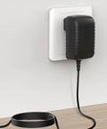 Wall AC Power Adapter For Casio AD-E95100B Keyboard plugged into wall showing black slim design and cable on wooden surface