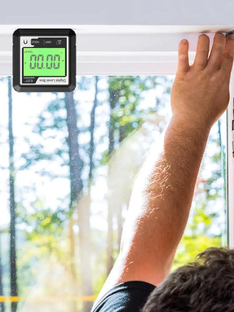 Knockout Performance Digital Angle Finder With Heavy Duty Magnetic Base And Bright Backlit Lcd Display functions as a sleek protractor inclinometer level box for dead on accuracy, held above a window frame.