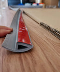 6.6 Ft Long Floor Transition Strip Edge Reducer gray with self-adhesive backing, beveled ramp on hardwood surface.