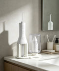 Water Flosser Stand Drying Rack For Cordless 3000 Series With Elevated Drainage on bathroom countertop next to sink mirror.