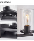 Detailed view of matte black four light vanity fixture with clear glass shades, modern wall sconce for mirror and hallway.