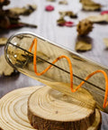 Cozy Amber Glow T10 LED Filament Bulbs 2200K Warm White 7.3 Inch Long Tubular E26 Base 40W Equivalent 400 Lumens Dimmable Vintage Edison Style Bulb Pack Of 4 lying on wood surface