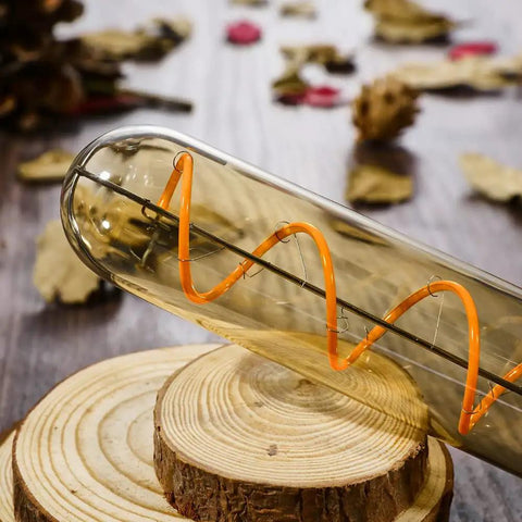 Cozy Amber Glow T10 LED Filament Bulbs 2200K Warm White 7.3 Inch Long Tubular E26 Base 40W Equivalent 400 Lumens Dimmable Vintage Edison Style Bulb Pack Of 4 lying on wood surface