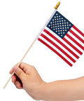 Hand holding one of the Pack Of 100 Small 4x6 Inch American Flags On 12 Inch Wood Sticks For Outdoor Use highlighting the size and design.