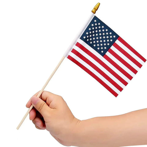 Hand holding one of the Pack Of 100 Small 4x6 Inch American Flags On 12 Inch Wood Sticks For Outdoor Use highlighting the size and design.