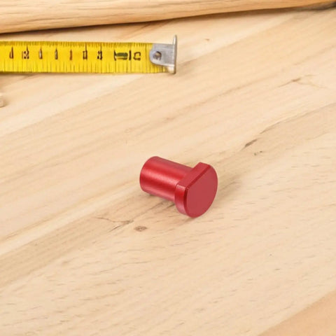 Red piece from Six Piece Aluminum Alloy Workbench Stops Set With Scratch Resistant Clamp And Quick Tightening Ratchet for woodworking shown on wood
