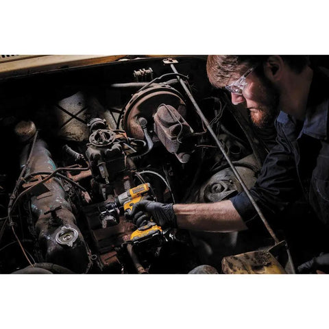 Man using 12V Max Cordless Three Eighths Inch Impact Wrench Tool Only With Brushless Motor on car engine in garage