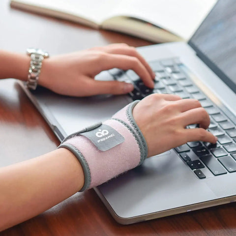 Person typing on laptop wearing Two Pack Copper Wrist Braces For Carpal Tunnel Pain Relief Arthritis And Tendonitis Adjustable All Day.