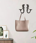 Hella Sturdy Mermaid Cast Iron Hooks holding a beige handbag on a wall, decorative storage solution for cozy spaces.
