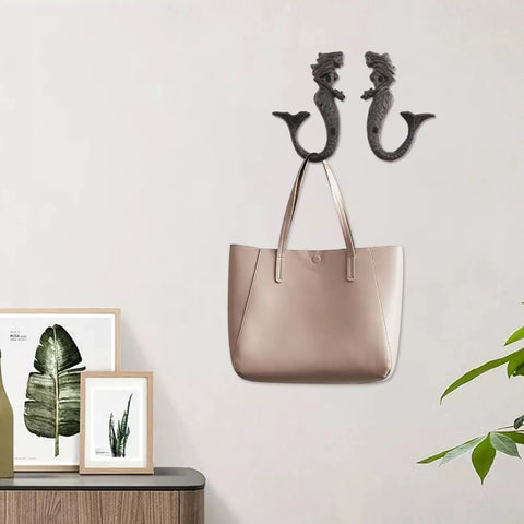 Hella Sturdy Mermaid Cast Iron Hooks holding a beige handbag on a wall, decorative storage solution for cozy spaces.