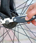 Hand using multitool from 27 Piece Bike Repair Kit With 16-In-1 Multitool And Tire Levers For E-Bikes on bicycle wheel bolt