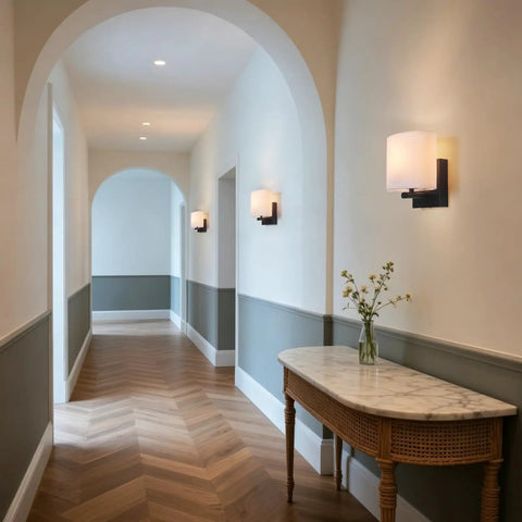 AuroraSpher Indoor Hardwired Modern Milky White Acrylic Black Wall Sconce elegantly lit hallway with wooden floor and archway.