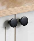Close-up of matte black cabinet knobs set ten pack one and a quarter inch round solid zinc alloy drawer pulls on a wooden cabinet