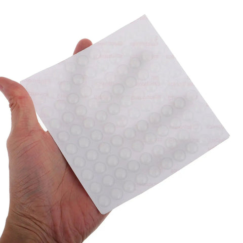 Hand holding sheet of Clear Silicone Furniture Pads 200 Pack No Slip Bumpers For Chair Legs Table Feet Cabinets Doors Floor Protection and Noise Dampening