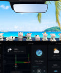 Front view of eight small white cow dashboard ornaments lined along car dash, with ocean view through windshield.