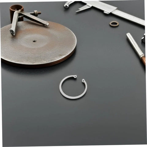 Five Piece Stainless Steel C Clips Kit For Grooved Shafts Heavy Duty Retaining Snap Rings Set With Multiple Sizes For Everyday Pro Grade Use And Quick Secure Fit on a workbench with tools.
