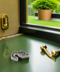 Sleek Plastic Fridge Door Stopper With Reliable Catch Hook For Modern Kitchens, clear plastic latch and screws on a table.