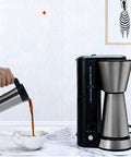 Fully Automatic Bean To Cup Coffee Maker With Integrated Milk Steam Wand Knocks Out Fresh Espresso and Frothy Lattes In Seconds with stainless steel thermal carafe pouring coffee.