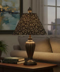 Stylish lamp with patterned shade in a cozy living room setting next to a sofa and artwork on the wall.