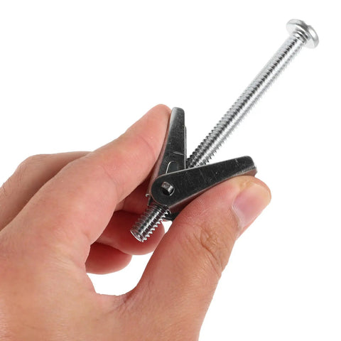 Close-up of hand holding galvanized iron toggle anchor from 24-Piece Toggle Anchors And Wing Nuts Bolts Kit For Drywall And Furniture Mounts.