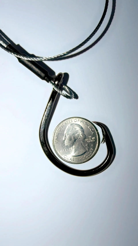 Close-up of 12/0 circle hook and braided wire from Beefy 3ft 480Lb Bite-Proof Stainless Leader for fishing, with a quarter for scale.
