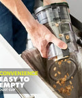 User empties the easy-to-empty dust cup of the Heavy Hitting Cordless Stick Vacuum Cleaner With 18 Volt Battery And Quick Charger.