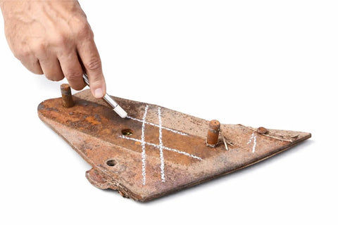 Hand using a soapstone to mark rusted metal with clear lines, demonstrating Welding Soapstone Refills 36 Pack For Metal Marking.