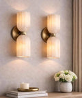 GLEAMING NEST Modern Alabaster Wall Sconce, Double Light Fixture, Antique Brass Finish, Fluted Stone Shades, Contemporary Wall Lamp for Bedroom, Living Room & Hallway, Brushed Chrome on textured wall.