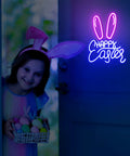 Easter Bunny Ears Neon Sign LED Light USB Powered Wall Decor For Living Room Bedroom Office Party Spring Decor Cute Table Art Gift Light Up Lit For Indoor Outdoor Vibes glowing on a wall next to a smiling child holding Easter eggs.