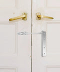 Automatic Stainless Steel Door Closer for Home and Office, Smooth Soft Close installed on white wooden door with brass handles