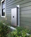 Heavy Duty Tankless Water Heater Indoor Outdoor Propane Natural Gas Compatible mounted on green wall with surrounding shrubs.