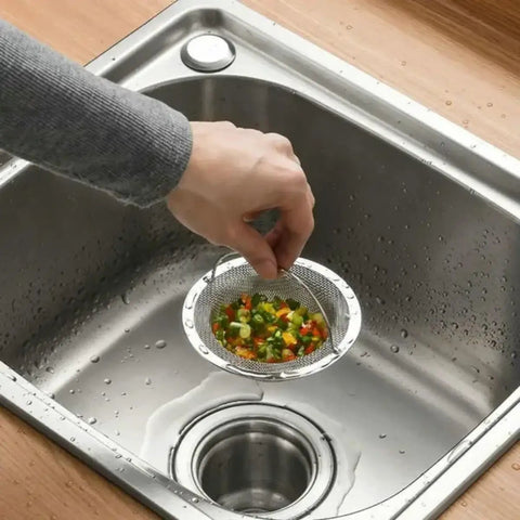 Ditch the Plumbing Headache Forever with This Tough Stainless Steel Sink Strainer Mesh Drain Catcher Filter Screen Traps Hair Food Crumbs and Bathtub Gunk while Keeping Things Moving Smooth; hand holding strainer with chopped vegetables over sink.