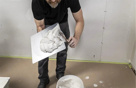 Man using Masonry Hawk With 13 Inch Aluminum Blade And DuraSoft Handle to hold plaster for drywall work, showcasing USA craftsmanship.