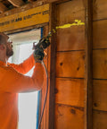 Professional Grade Interior Air Sealant Kicks Drafts To The Curb And Locks Warmth In Along Wall Ceiling Floor Joints Yellow 5 Gallon Big Bucket applied by a worker.
