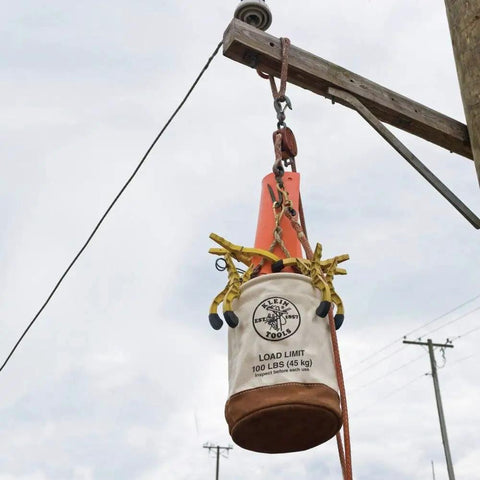 12 Inch Canvas Utility Bucket With Leather Bottom And Reinforced Leather Rim hanging from a pole outdoors
