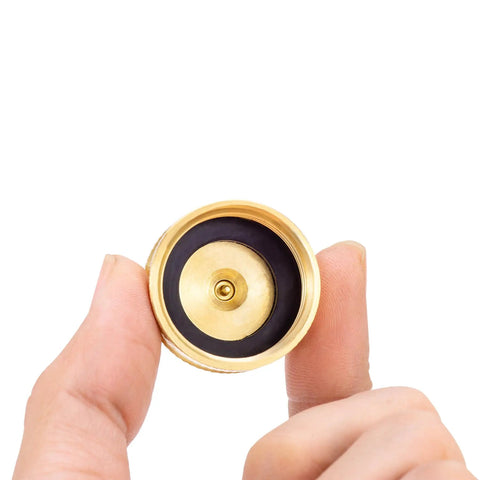 Top view of Beast RV Brass Blow Out Plug Adapter 3/4 Inch GHT Female And Male Garden Hose Quick Connect held between fingers.