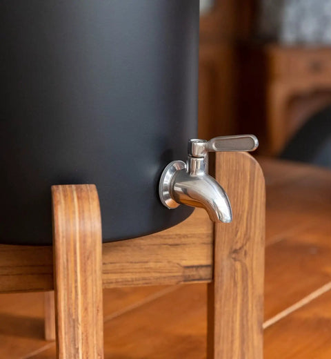 Close-up of stainless steel tap on 2.25 Gallon Gravity Water Filter System With Dual Activated Carbon Filters, wooden stand visible