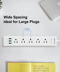 Two Prong To Three Prong Power Strip With Five Outlets And Three USB Ports Five Foot Extension Cord Surge Protector Up To 1625W Polarized Grounded Outlet Converter Wall Mountable Black shown with wide spacing and planted on a white surface with books and laptop in view