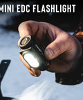 Person holding mini EDC flashlight outdoors