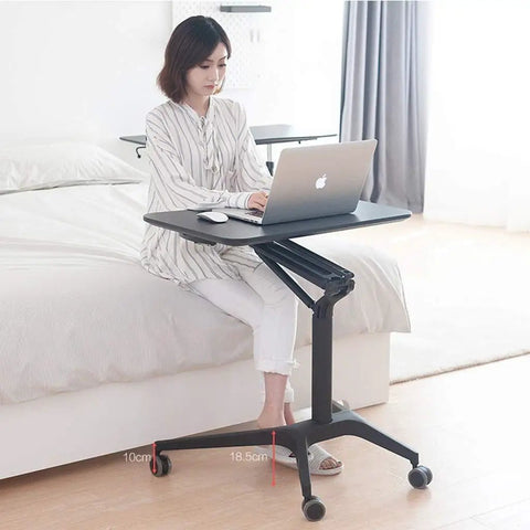 Zero Stress Height Adjustable Standing Desk With Smooth Roll Mobile Laptop Cart And Weight Bearing Pneumatic Lift For Relaxed Home Office Flex Setup White, in use beside bed.