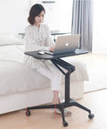 Woman working on Smooth Rolling Mobile Standing Desk With Pneumatic Height Adjustable Laptop Cart in bedroom.