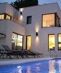 Modern home with Outdoor Porch Light 2 Pack Dusk to Dawn Photocell Sensor Wall Sconces illuminating the exterior, near pool at dusk