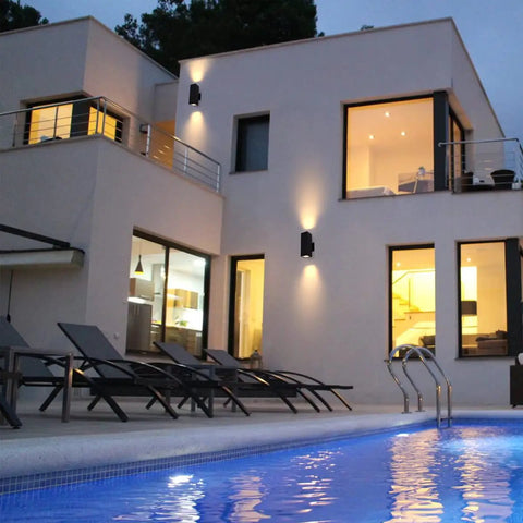 Modern home with Outdoor Porch Light 2 Pack Dusk to Dawn Photocell Sensor Wall Sconces illuminating the exterior, near pool at dusk